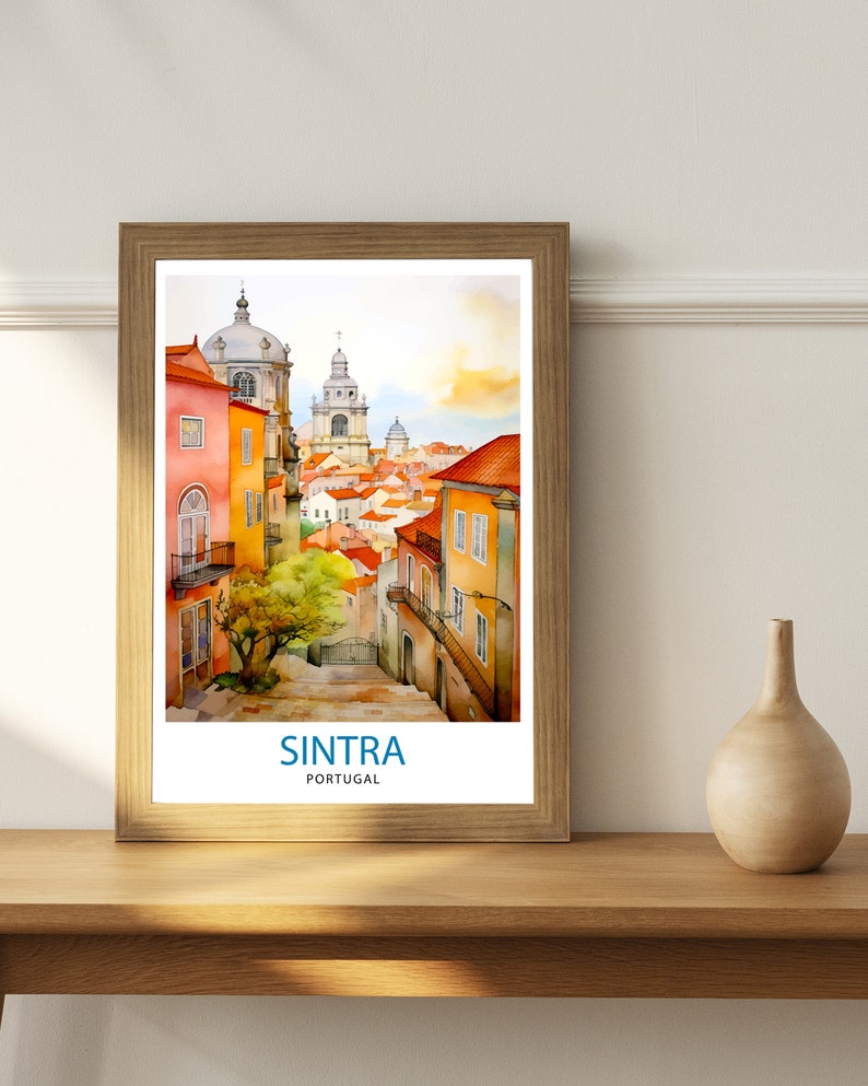 Puede incluir: Una pintura de acuarela enmarcada de una escena callejera en Sintra, Portugal. La pintura presenta una calle estrecha bordeada de edificios coloridos, un peque&ntilde;o &aacute;rbol y una vista de la ciudad en la distancia. El texto "SINTRA PORTUGAL" est&aacute; impreso en la parte inferior de la pintura.