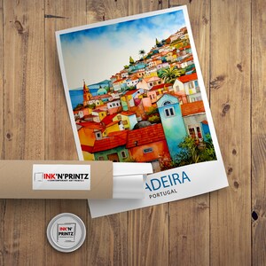 以下が含まれることがあります： カラフルな街並みを水彩で描いた絵画で、下部に「MADEIRA PORTUGAL」の文字があります。絵画は額装されており、すぐに飾ることができます。