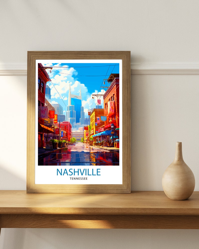 May include: A framed print of a colorful illustration of a street scene in Nashville, Tennessee. The print features a tall building in the background and a street lined with shops and buildings. The text "NASHVILLE" and "TENNESSEE" is printed below the image.