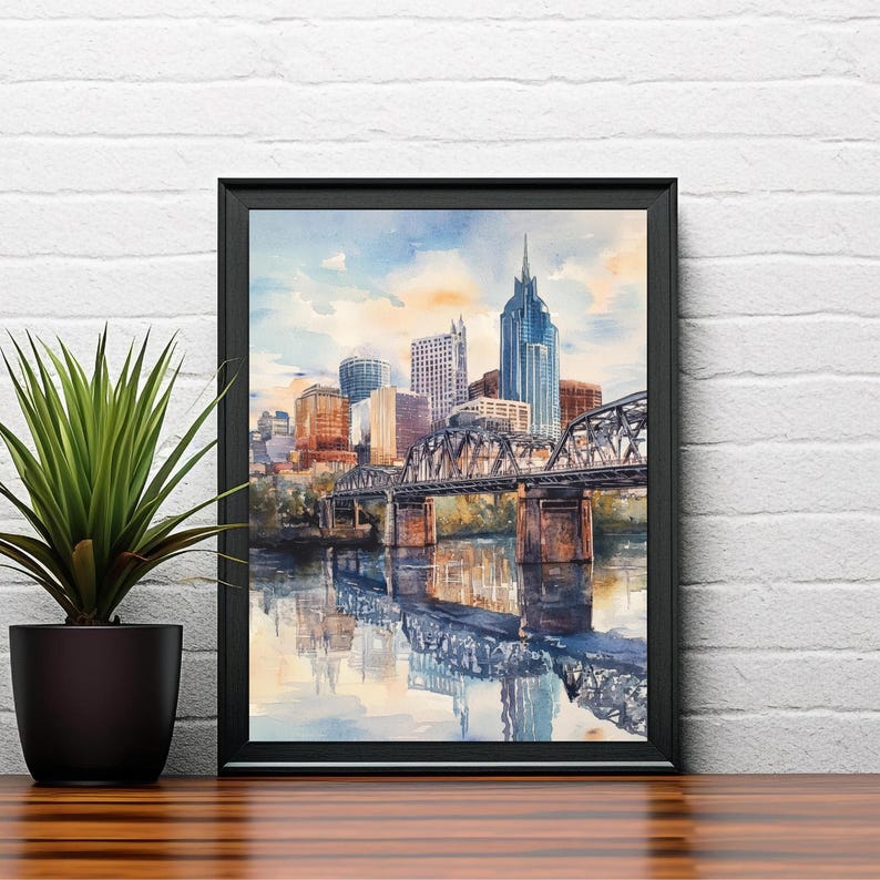 May include: A watercolor painting of the Nashville skyline with a bridge in the foreground. The buildings are painted in shades of gray, brown, and white, and the bridge is painted in shades of gray and brown. The water is painted in shades of blue and green.