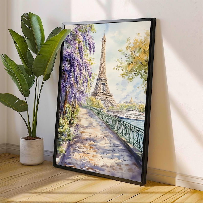 K&ouml;nnte beinhalten: Ein Aquarellbild des Eiffelturms in Paris, Frankreich. Der Turm ist von B&auml;umen und Blumen umgeben, und ein Weg f&uuml;hrt zu ihm hinauf. Das Bild ist in einem schwarzen Rahmen gerahmt.