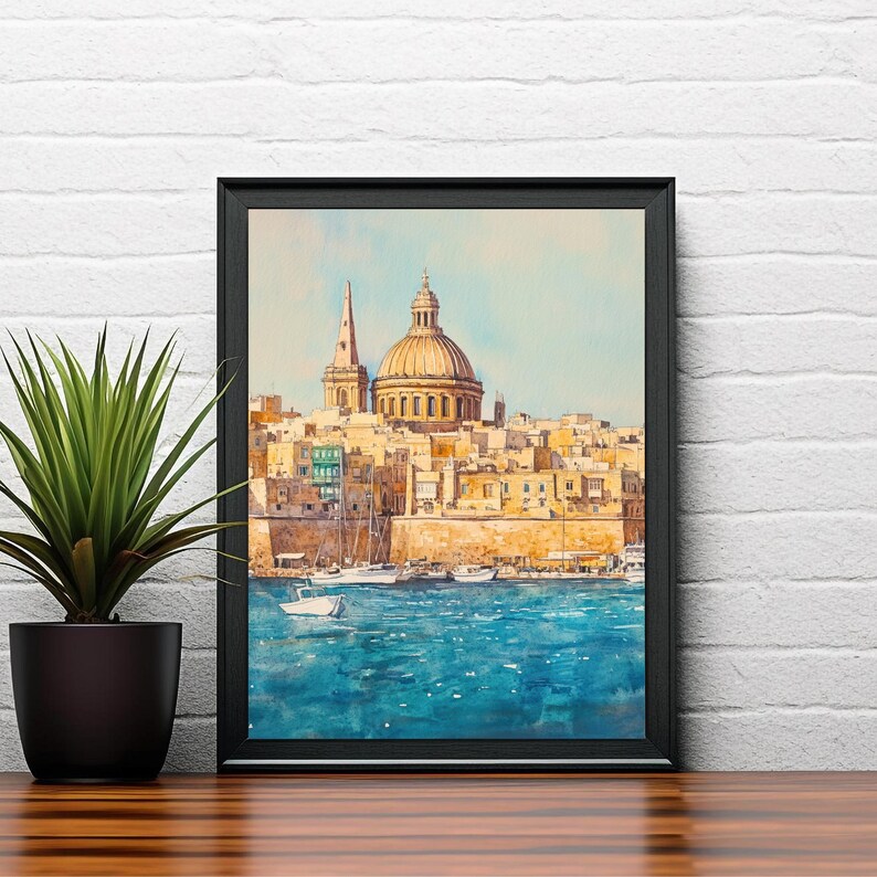 May include: A framed watercolor painting of a coastal city with a large domed building and a tall spire. The artwork features a vibrant blue sea and a warm color palette of yellows and oranges. A potted plant sits to the left of the frame.
