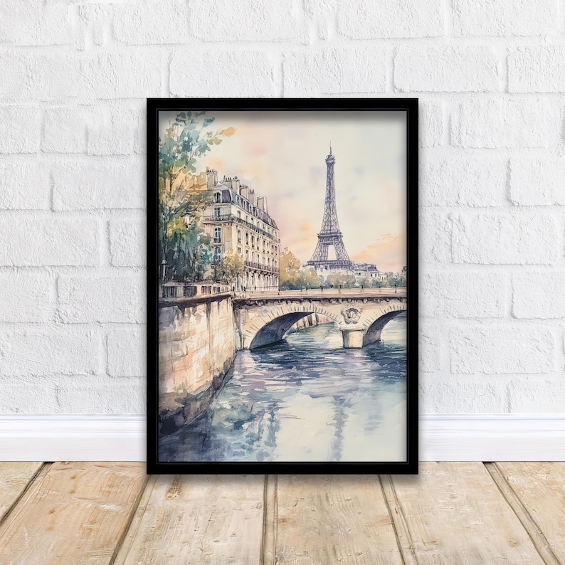 Op de afbeelding: Een aquarel schilderij van de Eiffeltoren in Parijs, Frankrijk. De schildering toont een brug over een rivier met gebouwen aan de linkerkant van het beeld. De lucht is lichtblauw met roze en oranje wolken.
