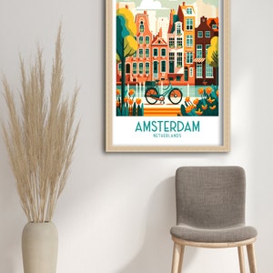 K&ouml;nnte beinhalten: Eine gerahmte Illustration einer farbenfrohen Stadtlandschaft mit einem Fahrrad im Vordergrund. Der Text "AMSTERDAM NIEDERLANDE" befindet sich am unteren Rand des Bildes.