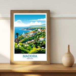 May include: A framed poster featuring a colourful illustration of a coastal town in Madeira, Portugal. The poster depicts a blue sky with white clouds, a blue ocean, green hills, and white buildings. The text "MADEIRA PORTUGAL" is printed at the bottom of the poster.