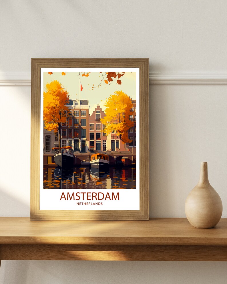 May include: A vintage travel poster with a colorful illustration of Amsterdam, Netherlands. The poster features a canal with boats and traditional Dutch houses with yellow trees in the foreground. The text "AMSTERDAM" and "NETHERLANDS" is printed in red at the bottom of the poster.