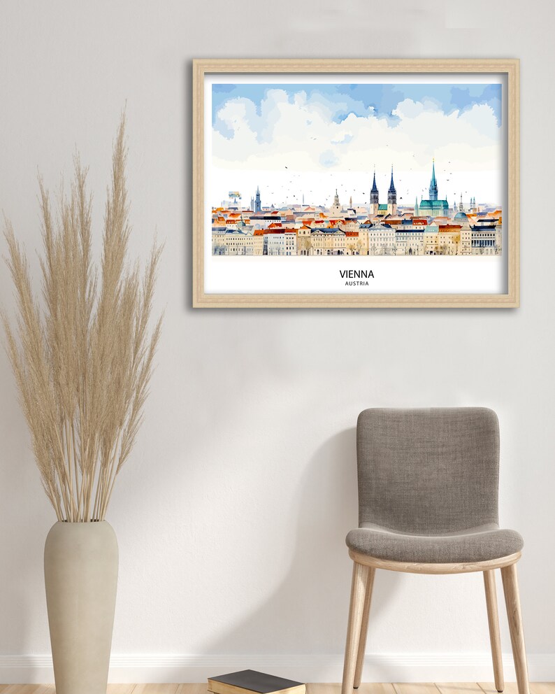 Peut inclure: Une peinture &agrave; l'aquarelle de l'horizon de Vienne, encadr&eacute;e dans un cadre en bois clair. La peinture repr&eacute;sente les b&acirc;timents embl&eacute;matiques de la ville, notamment la cath&eacute;drale Saint-&Eacute;tienne et le palais Hofburg. La peinture est plac&eacute;e sur un fond de ciel bleu avec des nuages blancs. Le texte "VIENNE, AUTRICHE" est imprim&eacute; sous la peinture.