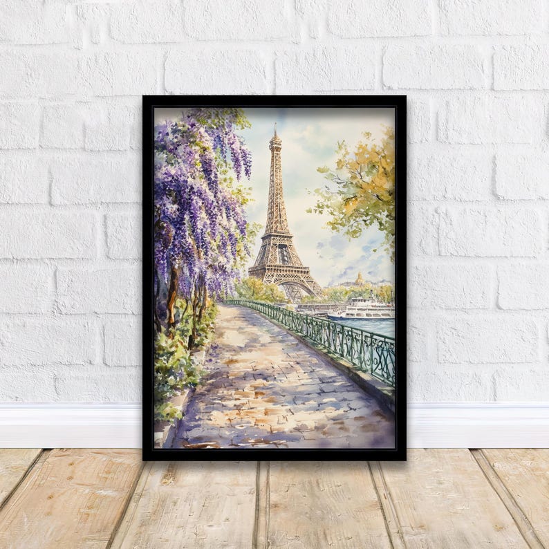 K&ouml;nnte beinhalten: Ein Aquarellbild des Eiffelturms in Paris, Frankreich. Der Turm ist von B&auml;umen und Blumen umgeben, und im Vordergrund befindet sich ein Fluss. Das Bild ist in einem schwarzen Rahmen gerahmt.