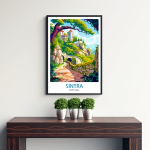 May include: A colorful illustration of a castle in Sintra, Portugal. The castle is perched on a hilltop with a winding path leading up to it. The illustration is framed in black and surrounded by green plants.
