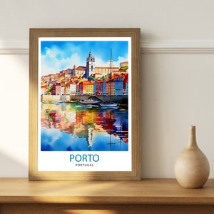 May include: A watercolor painting of the city of Porto, Portugal. The painting shows colorful buildings lining the waterfront with boats docked in the harbor. The water reflects the buildings and sky. The text "PORTO" and "PORTUGAL" is printed below the image.