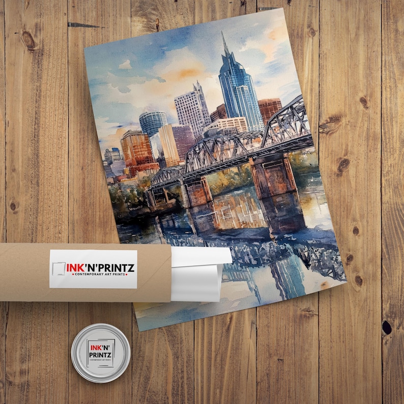 May include: A watercolor painting of the Nashville skyline with a bridge and river in the foreground. The buildings are painted in shades of blue, gray, and brown. The sky is a light blue with white clouds. The water is a dark blue with reflections of the buildings and bridge.