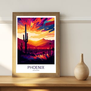 May include: A framed print depicting a colourful sunset over a desert landscape with a large cactus in the foreground. The print reads "PHOENIX ARIZONA".