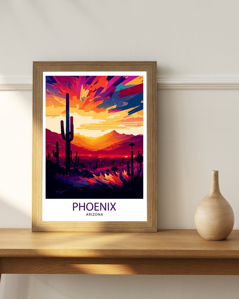 May include: A framed print depicting a colourful sunset over a desert landscape with a large cactus in the foreground. The print reads "PHOENIX ARIZONA".