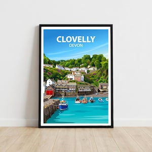 May include: A framed travel poster featuring a vibrant illustration of the coastal village of Clovelly, Devon. The artwork displays white buildings nestled on a green hillside above a harbour with several small boats on bright blue water.