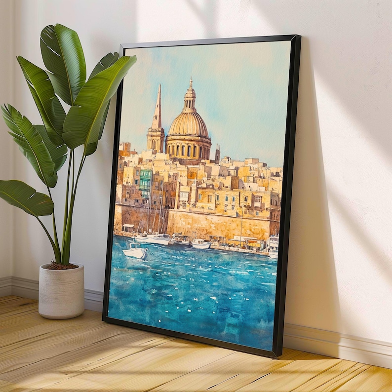 May include: Framed watercolor painting of a coastal city with a large domed building and a tall spire. The artwork features a vibrant blue sea with several boats, and the city is rendered in warm, earthy tones. The painting is displayed against a white wall.