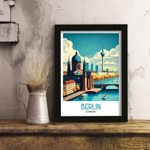 May include: A framed illustration of the Berlin skyline featuring the iconic Fernsehturm television tower, a church, and a bridge over a river. The illustration is in a vintage style with a blue, green, and orange color palette. The text "BERLIN GERMANY" is printed below the illustration.