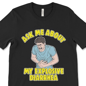 Puede incluir: Camiseta negra con un gráfico amarillo de un hombre sujetándose el estómago y el texto "Pregúntame sobre mi diarrea explosiva".