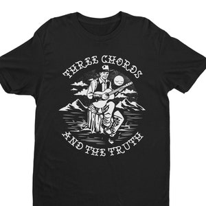 May include: Black t-shirt with a white graphic of a cowboy playing a guitar and the text "Three Chords and the Truth".