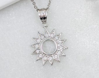 Peut inclure: Un collier argenté doté d'un pendentif en forme de soleil avec un centre circulaire et des rayons pointus. Le pendentif est orné de petites pierres claires et scintillantes serties le long de chaque rayon triangulaire, suspendu à une fine chaîne.