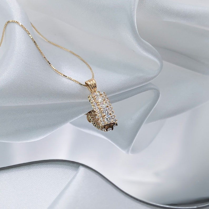 Puede incluir: Un collar de cadena de oro con un colgante de dise&ntilde;o rectangular con m&uacute;ltiples piedras peque&ntilde;as transparentes.