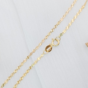 May include: A gold chain necklace with a delicate, floral pattern. The chain is made of small, interconnected flower-shaped links.