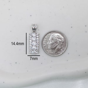Puede incluir: Un colgante de plata con forma rectangular y una fila de piedras de circonita c&uacute;bica transparentes. El colgante mide 14,4 mm de alto y 7 mm de ancho.