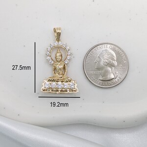 K&ouml;nnte beinhalten: Goldfarbener Anh&auml;nger mit einer sitzenden Buddha-Figur mit einem Heiligenschein aus klaren Zirkonia-Steinen. Der Anh&auml;nger ist 27,5 mm hoch und 19,2 mm breit.