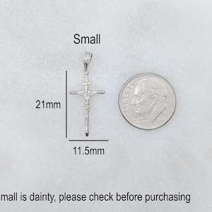 May include: A small, silver-colored crucifix pendant, measuring 21mm in length and 11.5mm wide, is displayed next to a dime for size comparison. The word "Small" is written above the pendant.