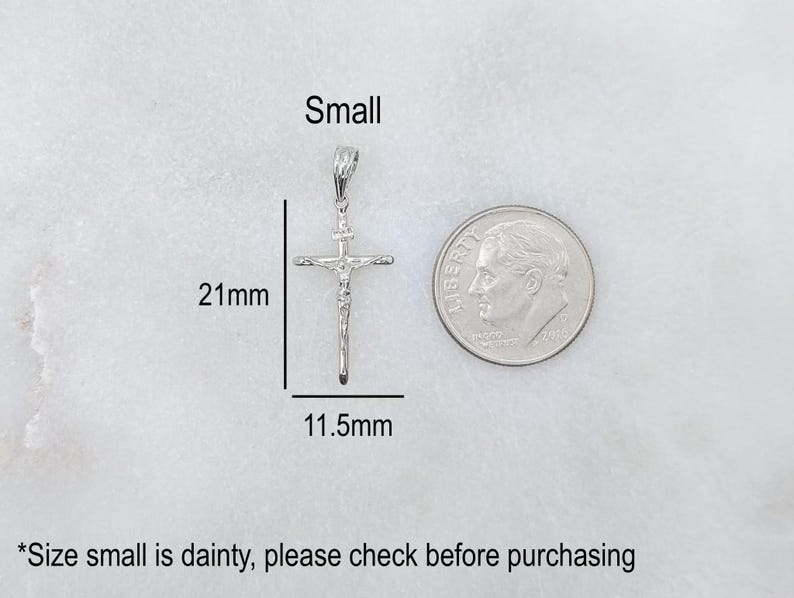 May include: A small, silver-colored crucifix pendant, measuring 21mm in length and 11.5mm wide, is displayed next to a dime for size comparison. The word "Small" is written above the pendant.