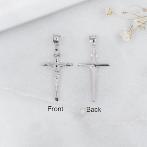 May include: Two silver-colored crucifix pendants, one showing the front and the other the back. The front pendant has a detailed depiction of Jesus on the cross. The word "Front" is below the front pendant, and "Back" is below the back pendant.