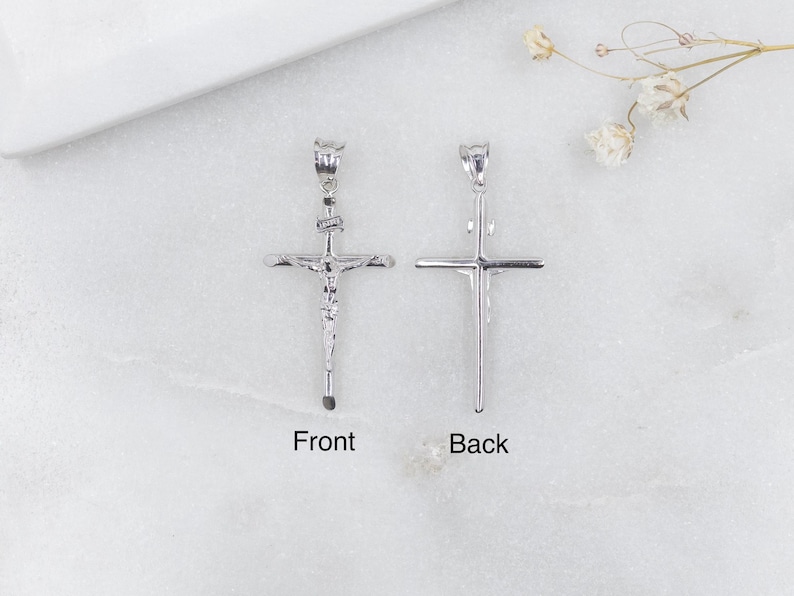 May include: Two silver-colored crucifix pendants, one showing the front and the other the back. The front pendant has a detailed depiction of Jesus on the cross. The word "Front" is below the front pendant, and "Back" is below the back pendant.