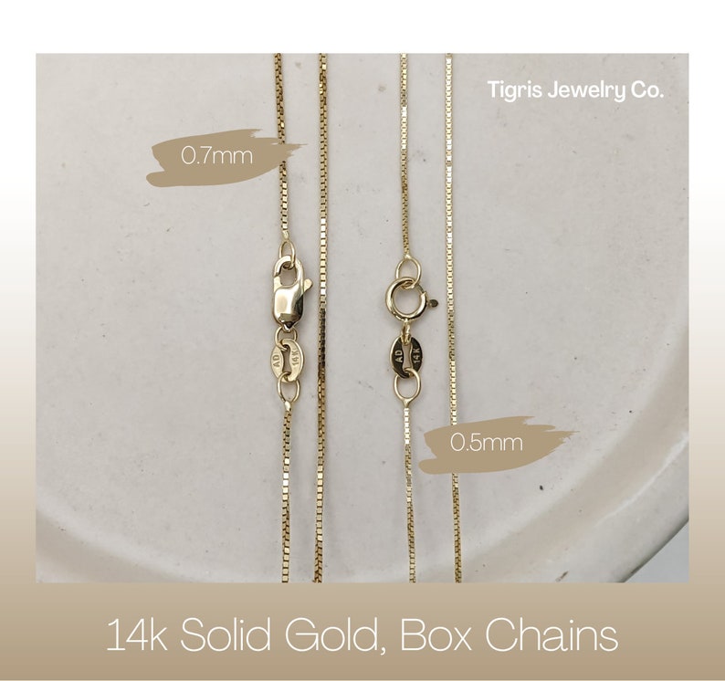 Puede incluir: Dos cadenas de caja de oro macizo de 14 quilates, una de 0,7 mm y otra de 0,5 mm, sobre una superficie blanca. Tigris Jewelry Co.