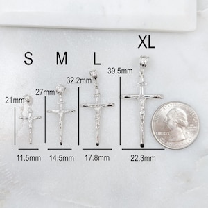 May include: A collection of silver crucifix pendants in various sizes, labeled S, M, L, and XL. Measurements are provided in millimeters, with the smallest pendant at 21mm and the largest at 39.5mm. A US quarter is included for size comparison.