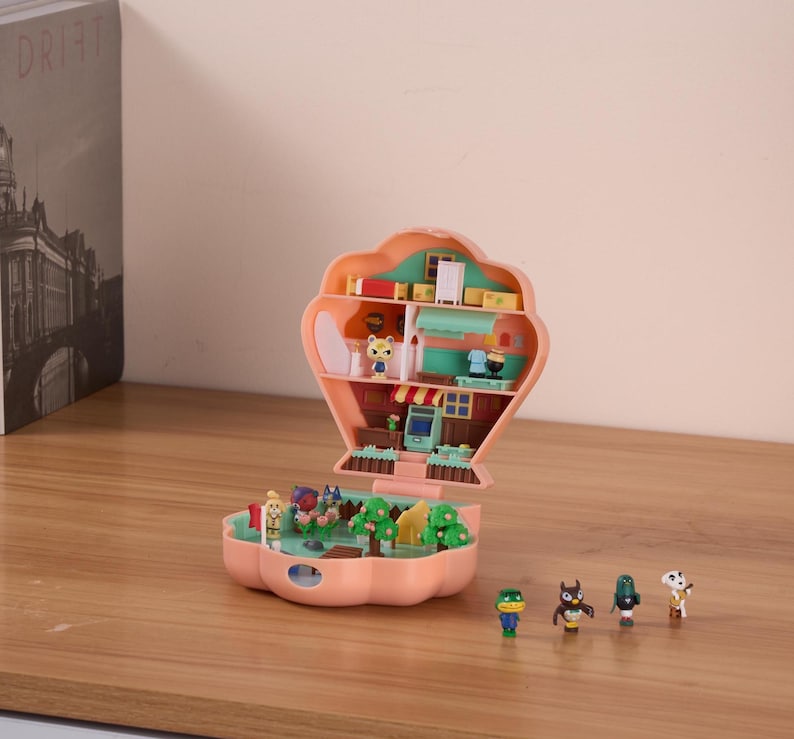May include: A pink and green plastic playset shaped like a seashell, open to reveal a miniature house with furniture and characters. The playset is on a wooden surface with five small figurines.