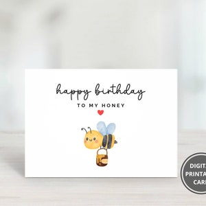 May include: A white printable birthday card with a cute cartoon bee carrying a pot of honey. The card says "happy birthday to my honey" with a red heart.