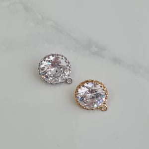 Puede incluir: Dos abalorios redondos de cristal transparente con un engaste de metal dorado y plateado. Cada abalorio tiene un pequeño lazo para sujetarlo a una joya.