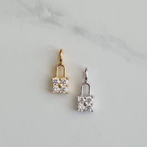 May include: Two lock charms with clear cubic zirconia stones. One charm is gold and the other is silver.