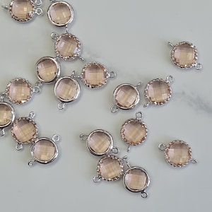 May include: A scattering of round, peach-coloured crystal connectors with silver metal frames. Each connector has a faceted surface and small loops for attachment. Suitable for jewellery making.