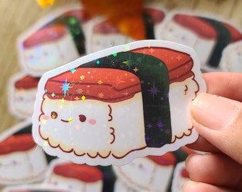 May include: A holographic sticker of a cartoon sushi with a red fish topping and a black seaweed wrap. The sushi has a cute face with a smile and closed eyes. The sticker has a glittery finish.
