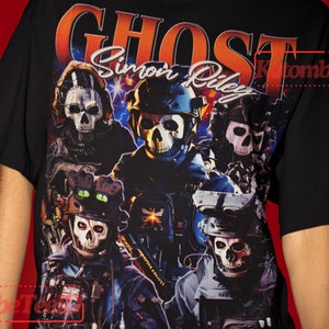 Puede incluir: Camiseta negra con un estampado gráfico de un grupo de soldados con máscaras de calavera. El texto "Ghost Simon Riley" está impreso en la camiseta.