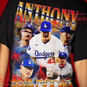 Puede incluir: Camiseta negra con un estampado gráfico de jugadores de béisbol que llevan uniformes de los Los Angeles Dodgers. El texto "ANTHONY" y "BANDIDA" está impreso en la camiseta.