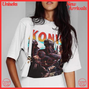 May include: White t-shirt with a graphic print of a band called "KONK" in a retro style. The graphic features a group of people in a futuristic setting.