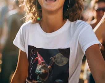 May include: White t-shirt featuring a whimsical illustration of a gnome playing a stringed instrument under a full moon. The shirt has the word "Chill" written on it. The person wearing the shirt is smiling and wearing sunglasses.