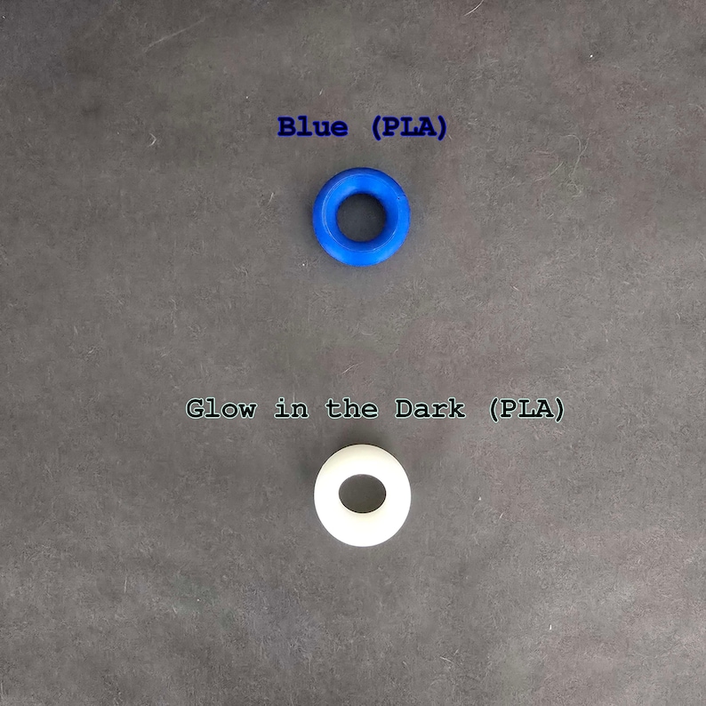May include: Two plastic rings, one blue and one white. The blue ring is labeled "Blue (PLA)" and the white ring is labeled "Glow in the Dark (PLA)".