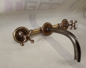 May include: A brass faucet with three cross-shaped handles and a curved spout. The faucet is mounted on a wall.