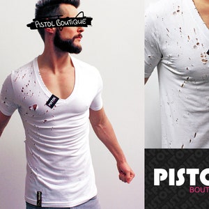 Könnte beinhalten: Weißes T-Shirt mit abgerissenen Löchern und V-Ausschnitt. Das Shirt hat ein kleines schwarzes Etikett mit dem Wort "PISTOL" darauf. Der Text "PISTOL BOUTIQUE" ist in Schwarz auf weißem Hintergrund über dem Kopf des Models geschrieben.