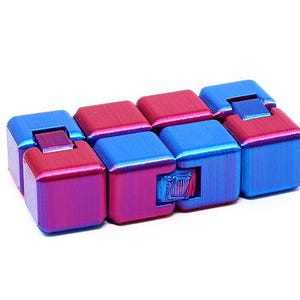 May include: A small, multi-colored fidget toy made of plastic. It is a cube shape with a series of smaller cubes that can be rotated and flipped. The toy is a mix of blue and purple.