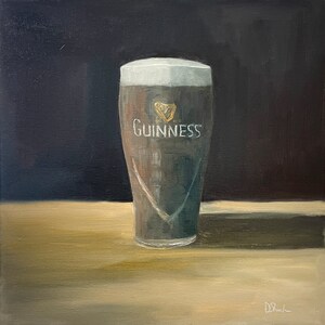 May include: A painting of a glass of Guinness beer on a wooden table. The glass is frosted and has the Guinness logo on it.