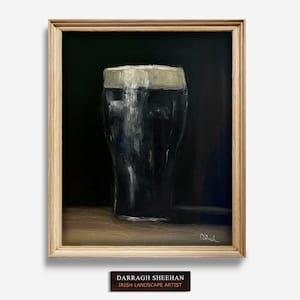 May include: Oil painting of a pint of stout in a wooden frame. The dark beer is topped with a creamy white head. The painting is signed and includes a plaque that reads "Darragh Sheehan, Irish Landscape Artist."