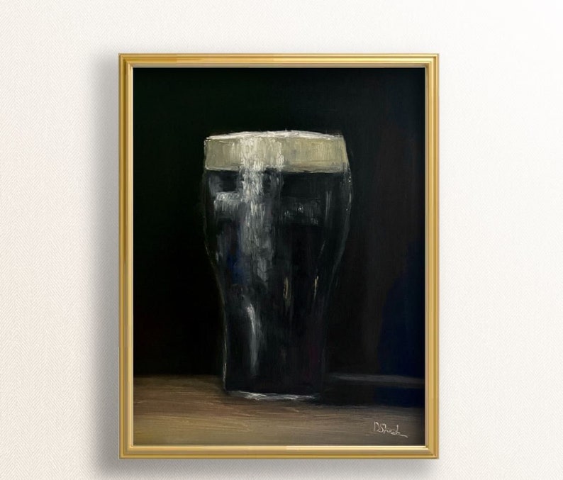 May include: An oil painting of a pint of stout in a gold frame. The dark beer is topped with a thick, creamy head. The background is a dark, solid color, and the painting is signed in the lower right corner.